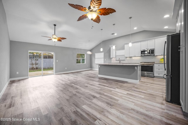 kitchen featuring stainless steel appliances, backsplash, decorative light fixtures, a center island with sink, and white cabinets