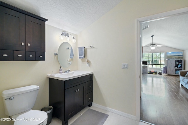 bathroom featuring vanity, vaulted ceiling, ceiling fan, toilet, and a textured ceiling