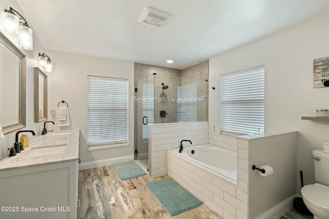 full bathroom featuring separate shower and tub, a textured ceiling, toilet, vanity, and hardwood / wood-style flooring