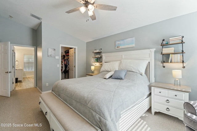 bedroom with ceiling fan, light colored carpet, lofted ceiling, a walk in closet, and a closet