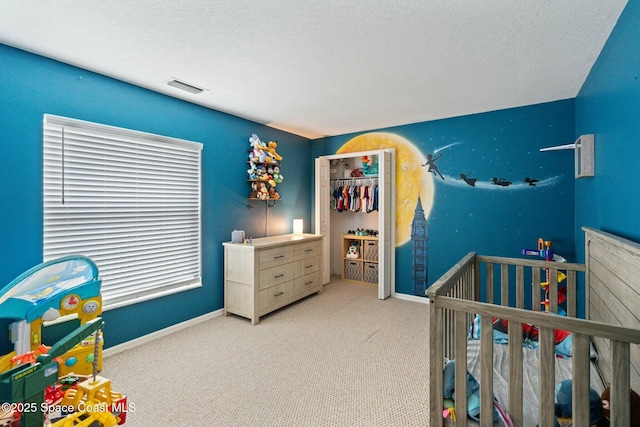 carpeted bedroom featuring a textured ceiling and a nursery area