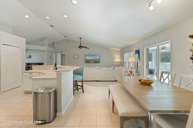 dining space with ceiling fan, lofted ceiling, and light tile patterned floors