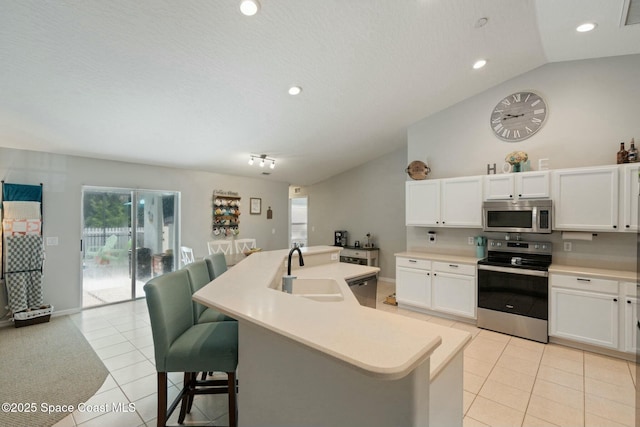 kitchen featuring a kitchen breakfast bar, stainless steel appliances, light tile patterned floors, and a center island with sink