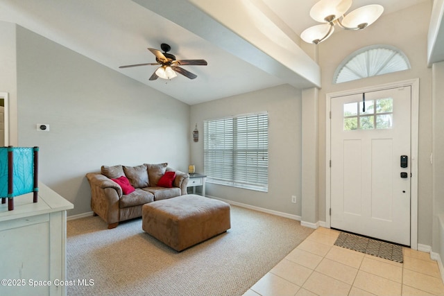 foyer entrance featuring ceiling fan with notable chandelier, light tile patterned flooring, and vaulted ceiling