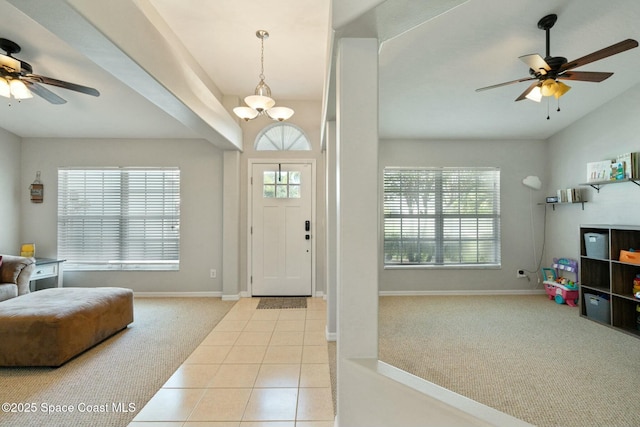 carpeted foyer with ceiling fan with notable chandelier