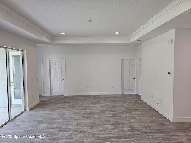 spare room featuring hardwood / wood-style flooring, a textured ceiling, a tray ceiling, and crown molding