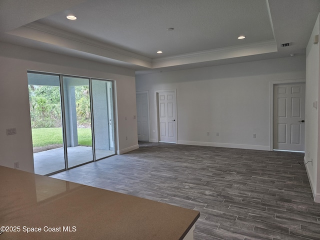 spare room with dark wood-type flooring, ornamental molding, and a raised ceiling