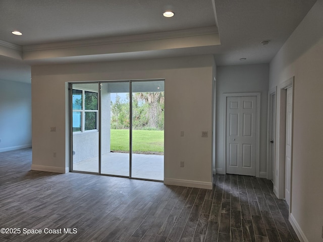 spare room with ornamental molding, dark hardwood / wood-style floors, and a tray ceiling