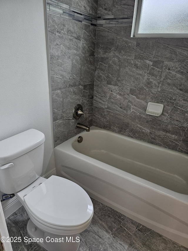 bathroom featuring toilet and tiled shower / bath