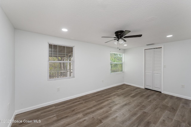 unfurnished bedroom featuring a textured ceiling, a closet, ceiling fan, and dark wood-type flooring