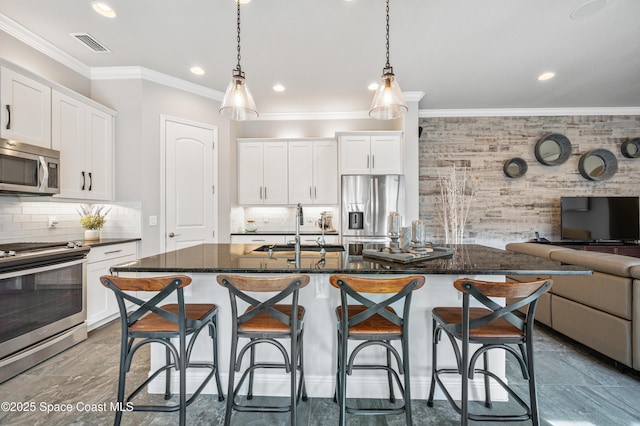 kitchen with a breakfast bar, sink, an island with sink, decorative light fixtures, and stainless steel appliances