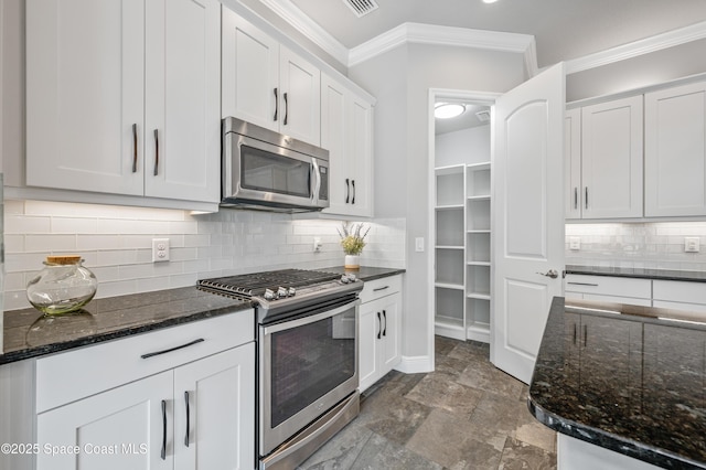 kitchen with white cabinets, stainless steel appliances, tasteful backsplash, and dark stone counters