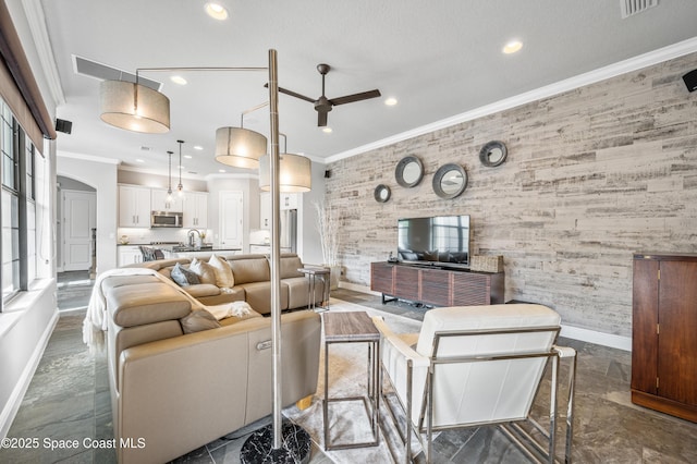 living room with ceiling fan, sink, and crown molding