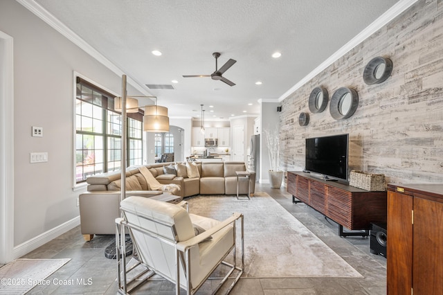 living room with a textured ceiling, ceiling fan, and crown molding