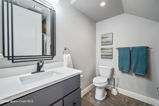 bathroom with a textured ceiling, vanity, vaulted ceiling, and toilet