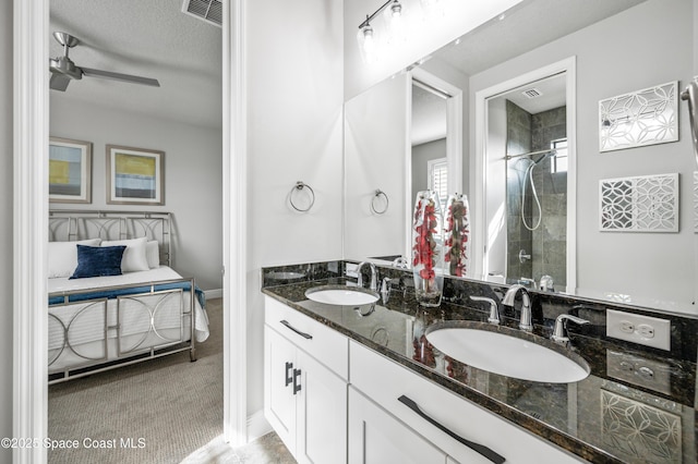 bathroom featuring vanity, ceiling fan, tiled shower, and a textured ceiling