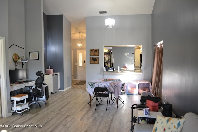 interior space featuring light wood-type flooring, a high ceiling, and an inviting chandelier