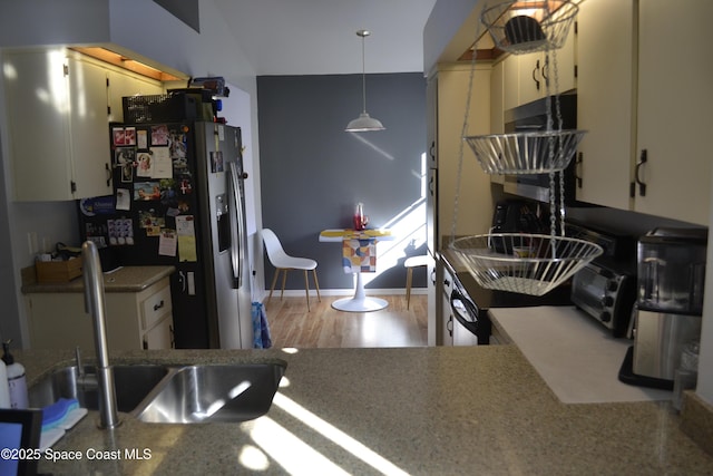 kitchen featuring sink, pendant lighting, light hardwood / wood-style flooring, white cabinets, and stainless steel fridge with ice dispenser