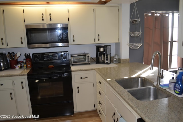 kitchen with light stone countertops, sink, light hardwood / wood-style flooring, white cabinets, and black electric range oven