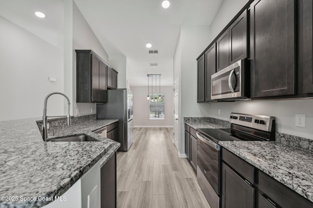 kitchen featuring light hardwood / wood-style floors, sink, light stone countertops, and stainless steel appliances