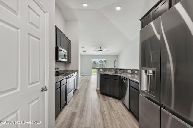 kitchen featuring ceiling fan, sink, stainless steel appliances, dark stone countertops, and light hardwood / wood-style floors