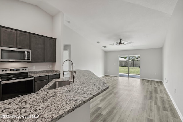 kitchen featuring light stone countertops, sink, ceiling fan, dark brown cabinets, and appliances with stainless steel finishes