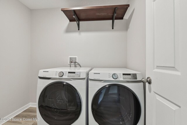 laundry room with washing machine and clothes dryer and hardwood / wood-style flooring