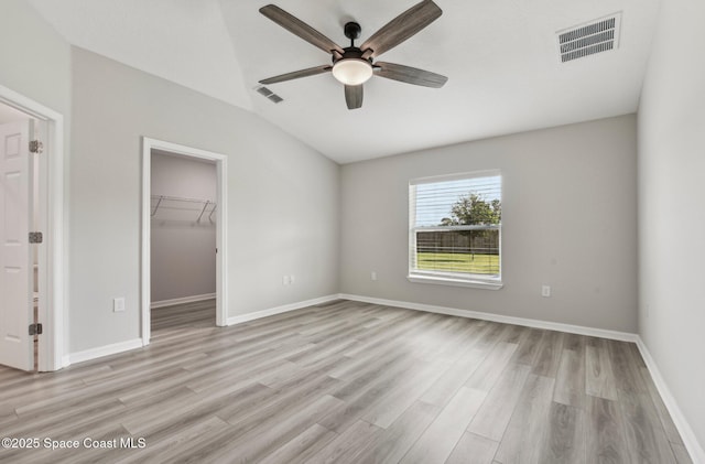 unfurnished bedroom featuring a spacious closet, a closet, ceiling fan, and light wood-type flooring