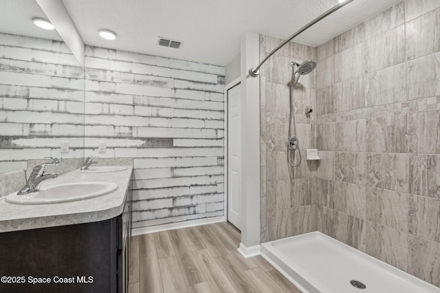 bathroom with a textured ceiling, vanity, hardwood / wood-style flooring, and walk in shower