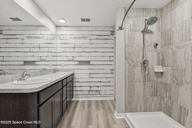 bathroom with hardwood / wood-style floors, vanity, and tiled shower