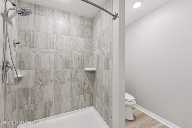 bathroom featuring tiled shower, hardwood / wood-style floors, a textured ceiling, and toilet