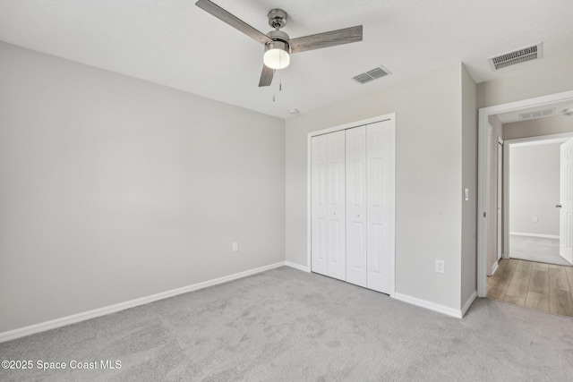 unfurnished bedroom featuring ceiling fan, light colored carpet, and a closet