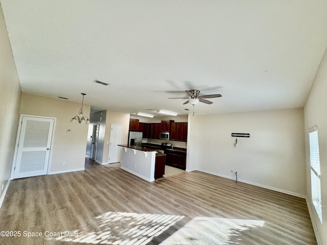 kitchen featuring a center island, pendant lighting, light hardwood / wood-style floors, ceiling fan with notable chandelier, and appliances with stainless steel finishes