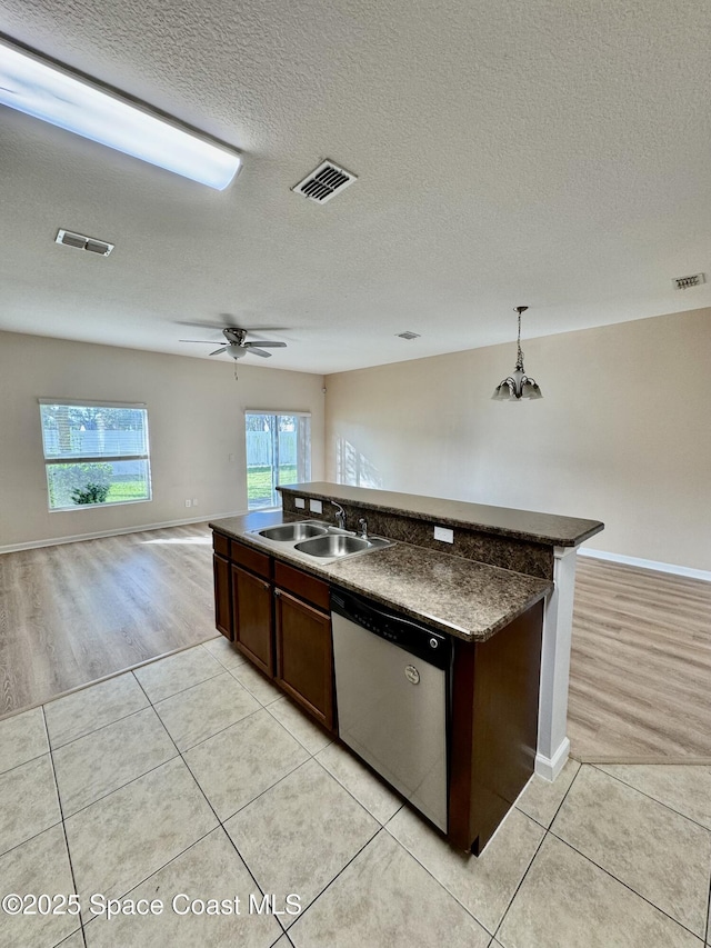 kitchen featuring sink, light tile patterned floors, stainless steel dishwasher, and decorative light fixtures