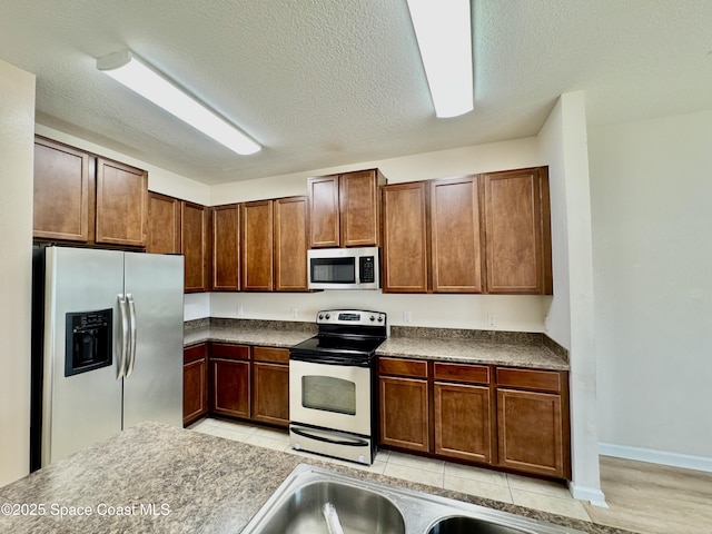 kitchen with appliances with stainless steel finishes, a textured ceiling, and sink