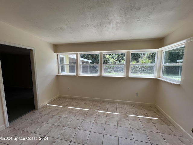 spare room with light tile patterned floors and a textured ceiling