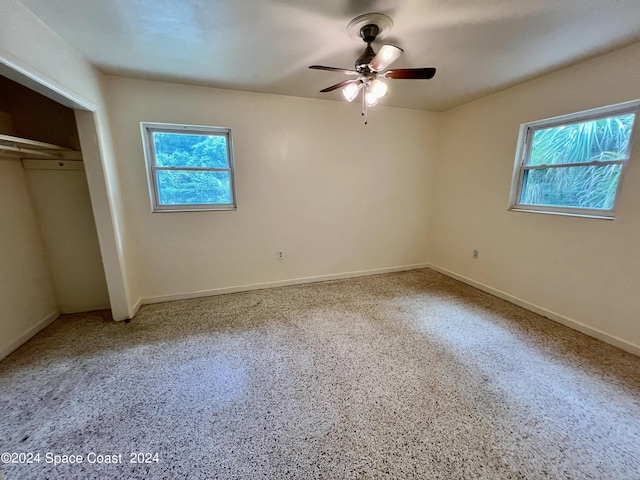 unfurnished bedroom with multiple windows, ceiling fan, and a closet