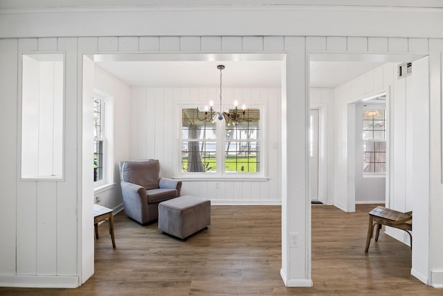 sitting room with plenty of natural light, wood-type flooring, crown molding, and a chandelier