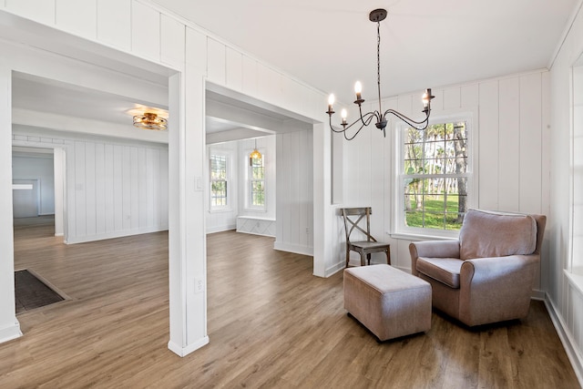 sitting room featuring wood-type flooring, crown molding, and a notable chandelier