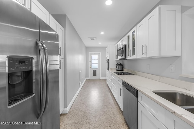 kitchen with light stone countertops, stainless steel appliances, white cabinetry, and sink