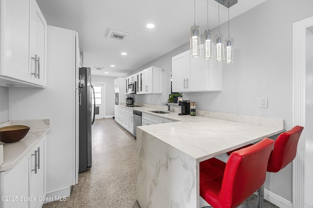 kitchen with light stone countertops, a breakfast bar, stainless steel appliances, sink, and white cabinets