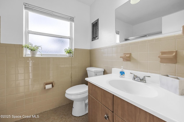 bathroom featuring tile patterned flooring, vanity, toilet, and tile walls