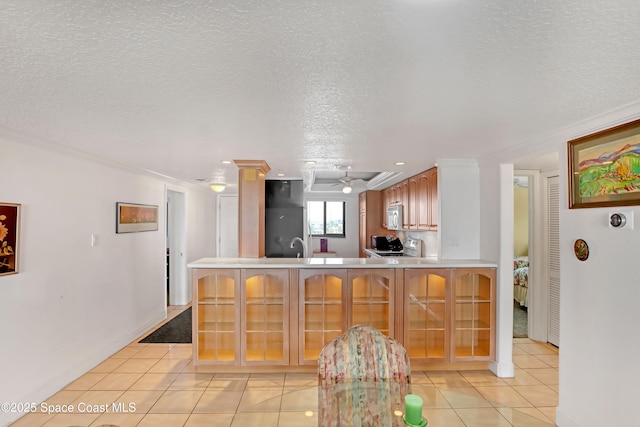 kitchen featuring kitchen peninsula, light tile patterned flooring, a textured ceiling, and ornamental molding