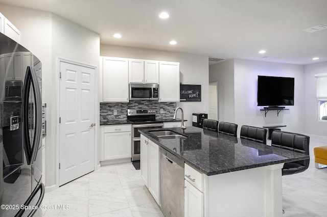 kitchen featuring appliances with stainless steel finishes, a kitchen breakfast bar, white cabinets, and sink