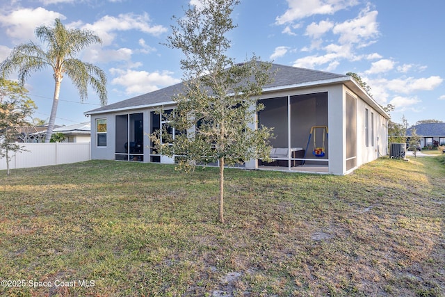 rear view of property featuring central AC, a lawn, and a sunroom