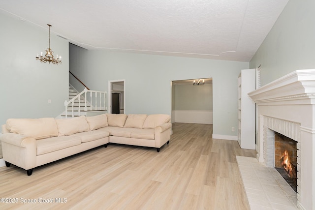 living room featuring light hardwood / wood-style flooring, a brick fireplace, and a notable chandelier