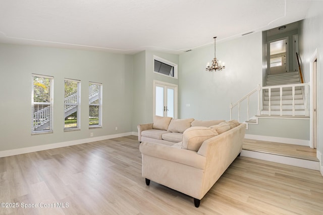 living room with french doors, light wood-type flooring, and a notable chandelier