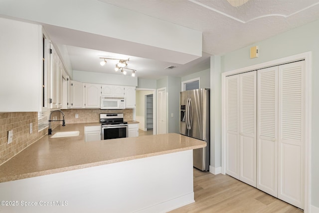 kitchen featuring kitchen peninsula, sink, white cabinets, and stainless steel appliances