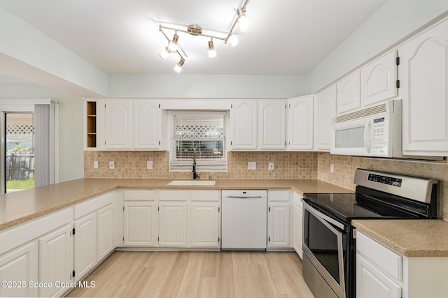 kitchen with white cabinets, light wood-type flooring, white appliances, and sink