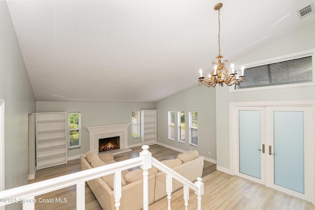 unfurnished living room with a healthy amount of sunlight, wood-type flooring, a fireplace, and a chandelier